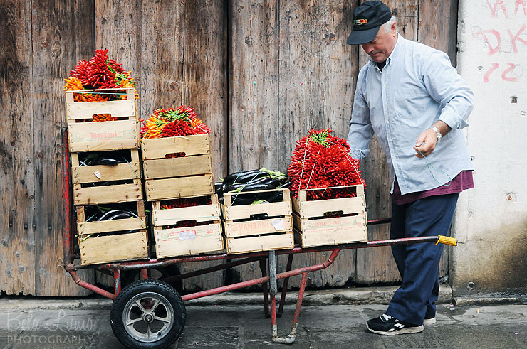 A market vendor readies a cartload of red and orange hot peppers. 
